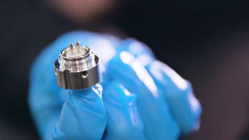 gros plan de gants bleus tenant une pièce de microscope