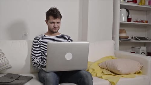 Man using laptop on sofa indoors during the daytime