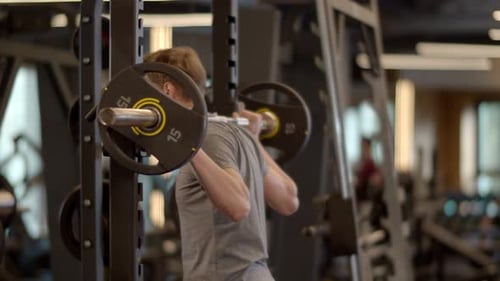 Closeup Handsome Fitness Man Doing Barbell Squats At Gym. Serious Bodybuilding Man Training In Sp...