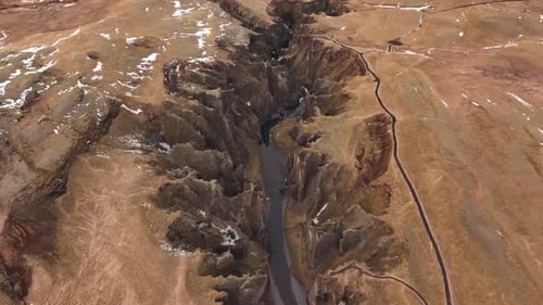 aerial - top view of Fjaðrárgljúfur canyon river slicing Icelandic plateau