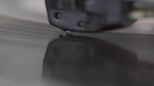 Extreme close up of the needle of a record player over the LP.