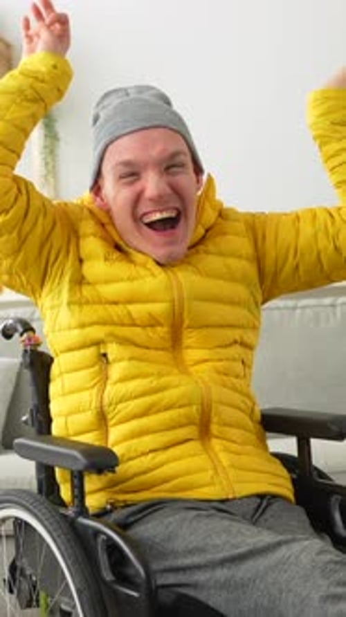 Happy disabled man in wheelchair raising hands in joy celebrating