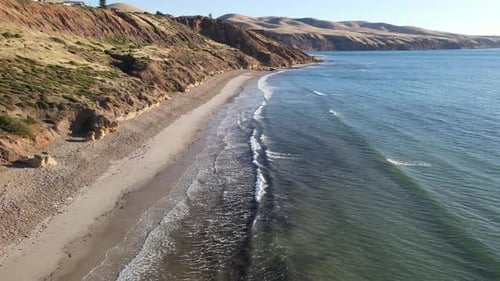 Cinematic drone shot over a calm Sellicks Beach, South Australia. SMall waves crashing in the foregr