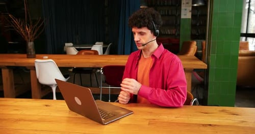 Call Center Operator Sales Manager Using Headset and Laptop Having Video Call Sitting in Office