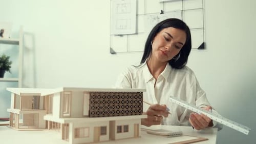 Professional architect using triangular scale measure house model. Immaculate.