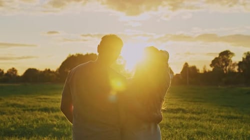 Couple Enjoys Sunset Together in a Serene Field on a Warm Evening