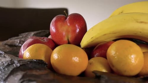 Pommes, mandarines et bananes dans un bol en bois. Fermer le curseur gauche.
