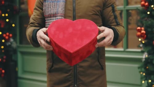 Man Holding Heart Shaped Gift Box in Snow