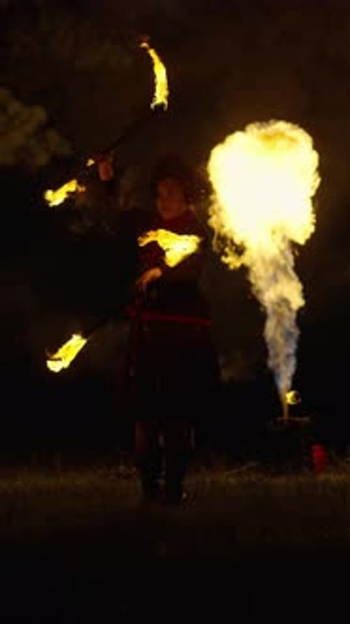 Mesmerizing Nighttime Fire Performance with a Dancer Twirling Blazing Torches in Flowing Costume