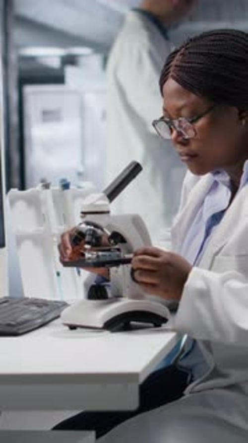 Vertical Video Black Scientist Examining Samples Under Microscope in a Modern Laboratory