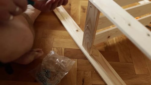 Man Assembling New Wooden Shelf and Furniture in the Apartment