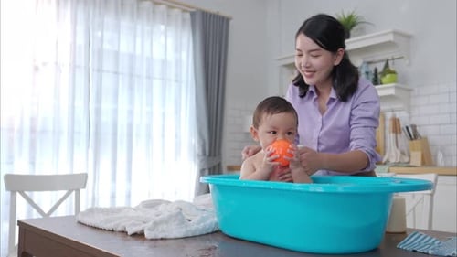 Mother Bathes Adorable Baby in Tub Indoors