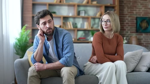 Upset Man and Woman Sitting on Couch Apart