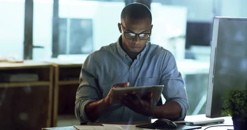 4k video footage of a young businessman working late on a digital tablet in an office