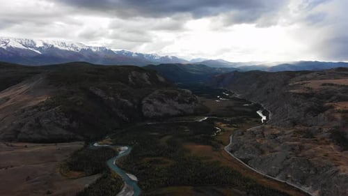 Camera Panning Over a Beautiful Mountain Valley with a Winding River Sunlight Shining on the Peaks