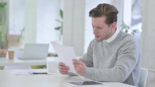 Frustrated Man Reading Documents in Bright Office