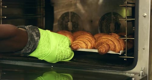 4k video footage of an unrecognizable baker removing croissants from the oven at a bakery