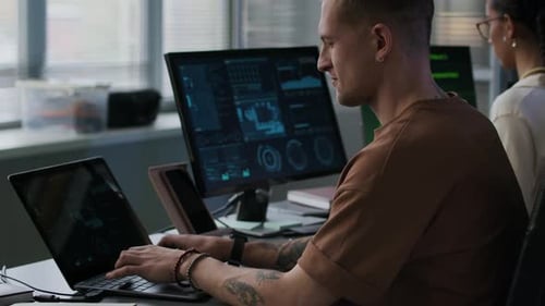 Young Multiethnic IT Specialists at Computer Desk in Office in Evening