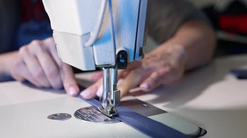 Female hands working on tailoring. Tailor working with sewing machine at fashion design workshop