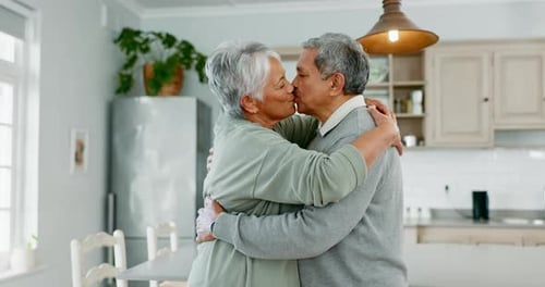 Senior Couple Sharing Affectionate Embrace in Kitchen