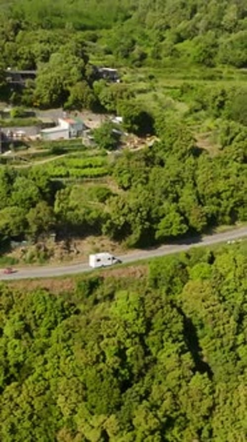 Vertical drone shot folllowing a RV driving on a dangerous, high altitude road