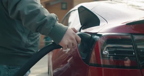 Man pulls out the charging cable from the electric car