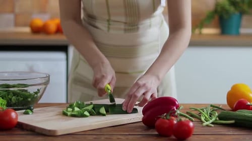 Woman Chopping Cucumber for Salad in Bright Kitchen
