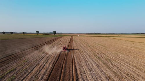 Tractor Working in Agricultural Field Cultivating and Plowing Dry Soil