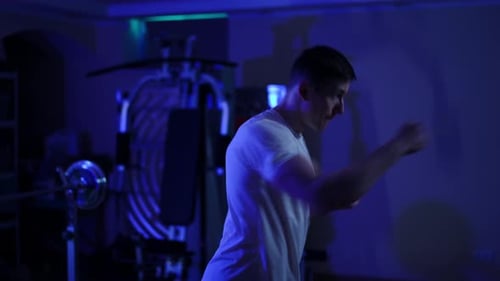 Side View Motivated Boxer Training in Darkness in Home Gym Medium Shot of Fit Strong Caucasian