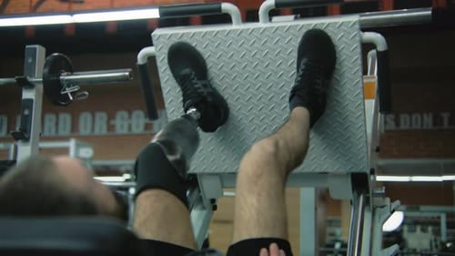 Man with Prosthetic Using Leg Press at Gym