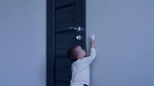 Criança caucasiana feliz brincando com interruptor de luz.