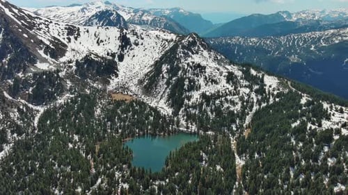 Mountain lake with snow mountains and green forest