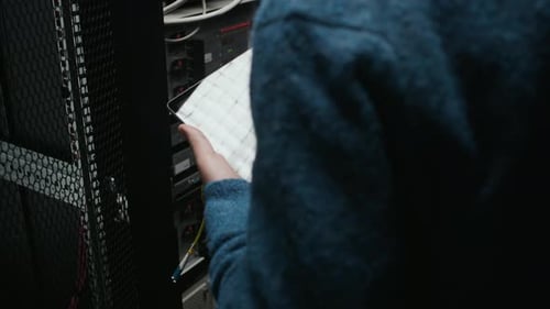 IT Technician Inspects Cables in Server Room