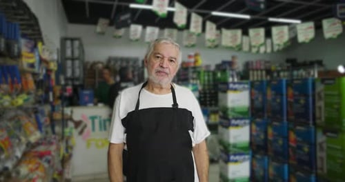 El dueño de una tienda, un hombre mayor, de pie casualmente en el pasillo de una ferretería,