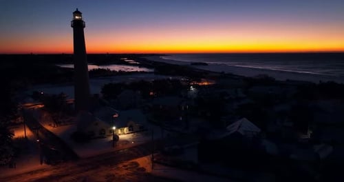 Lighthouse tower at night. Beautiful sunrise. Colorful sunset and ocean waves. Aerial orbit.