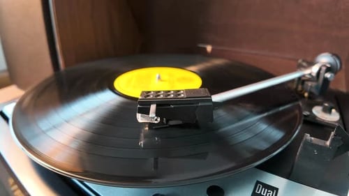Black vinyl Retro record on DJ turntable. Black vinyl background with a yellow screen in the center.