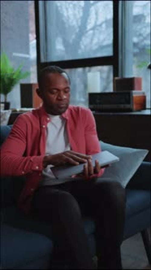 Man Sitting on Couch Opening Laptop