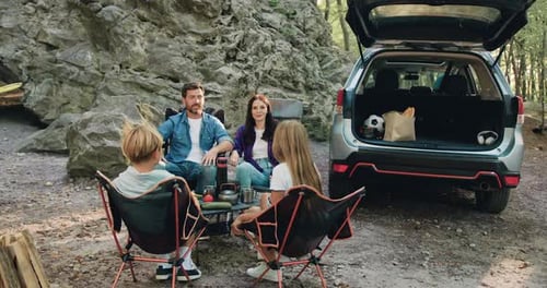 Happy family including mother, father, and two kids enjoying summer holidays in the garden or park.