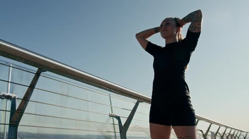 Fitness young sportswoman girl tired after doing sports training outdoors in the city on the bridge