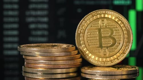 Close view of multiple physical Bitcoins with moving digital charts