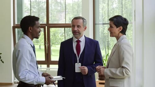 Three Businesspeople Talking in Office Building Lobby