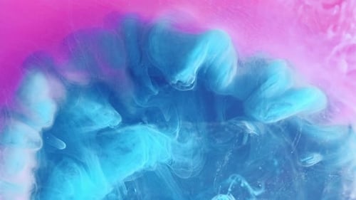 Abstract Blue Ink Swirling Through Pink Liquid