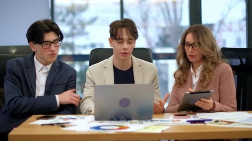 Business meeting in an office, female team leader and two young workers discussing business affairs