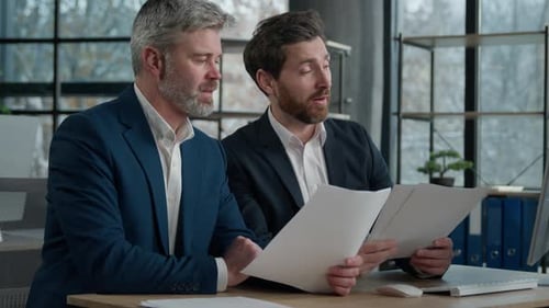 Two Caucasian Men Businessmen in Office Working Together on Financial Statistics Analyzing Charts