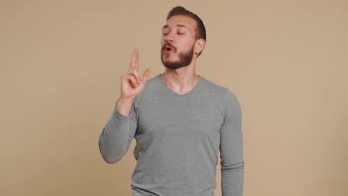 Man Pretending with Hand Pistol Against Beige Background