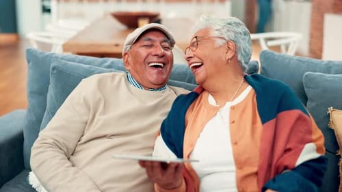 Senior Couple Laughing While Looking at Tablet