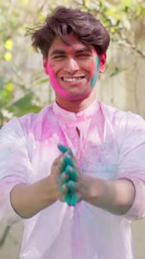 Smiling Man Covered in Holi Colors Claps Hands