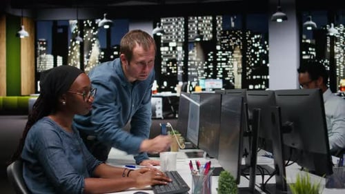 Coworkers Collaborate on Computer Code in Modern Office