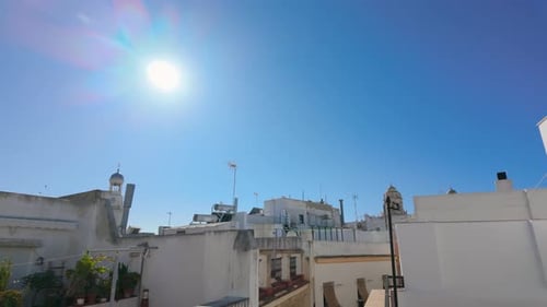 A rooftop view under a bright sun showcases the white-washed buildings typical of Andalusian archite