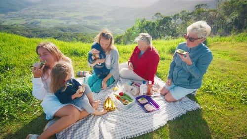 Big Family Have Picnic on the Green Hill in the Mountains at Sunrise